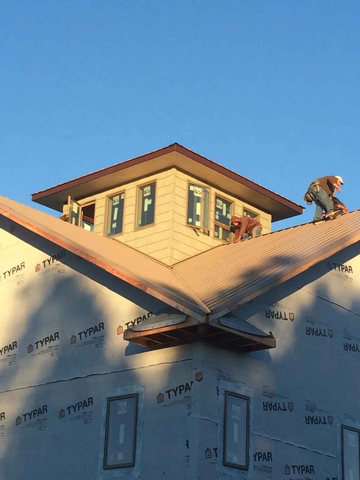 Roofers working around a rooftop cupola on a new metal roof at sunset — Roof Waterproofing in Atkinson by Roofing Brothers